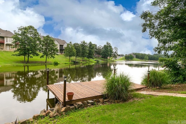 view of dock with a yard and a water view