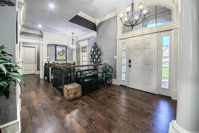 entryway featuring a textured ceiling, decorative columns, crown molding, and dark wood-type flooring