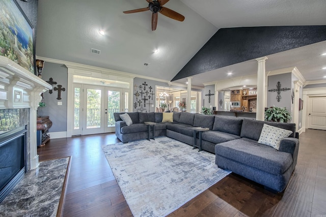 living room featuring decorative columns, a high end fireplace, dark hardwood / wood-style floors, and lofted ceiling