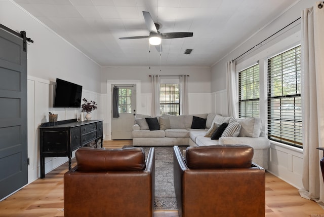 living room featuring a barn door, light hardwood / wood-style flooring, and plenty of natural light