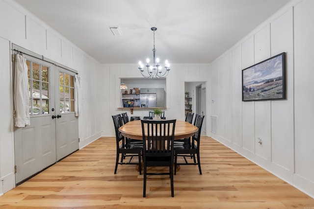 dining area with light wood-type flooring, ornamental molding, and an inviting chandelier