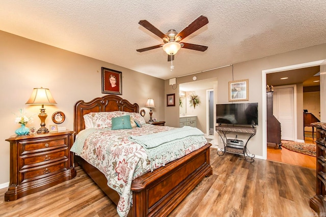 bedroom featuring hardwood / wood-style floors, a textured ceiling, ceiling fan, and connected bathroom