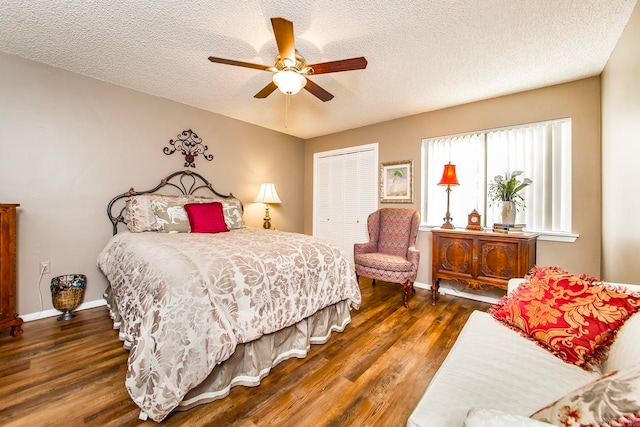 bedroom with a textured ceiling, ceiling fan, dark wood-type flooring, and a closet