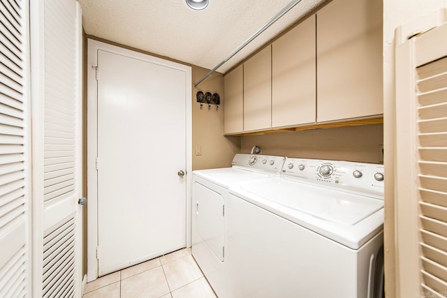 laundry room with washing machine and clothes dryer, light tile patterned flooring, cabinets, and a textured ceiling