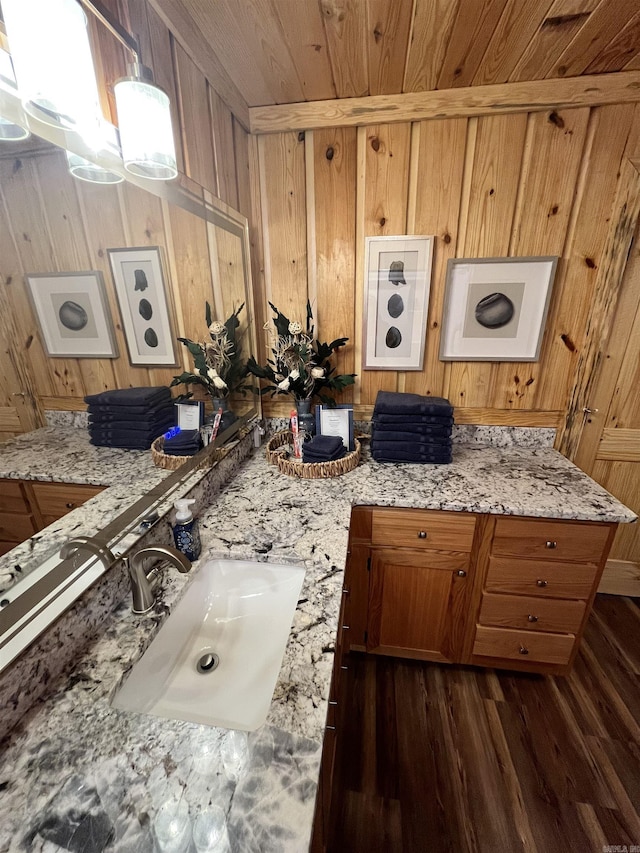 173 Henry Ln, Shirley, AR 72153 - kitchen with wooden walls, a sink, dark wood finished floors, brown cabinets, and light stone countertops