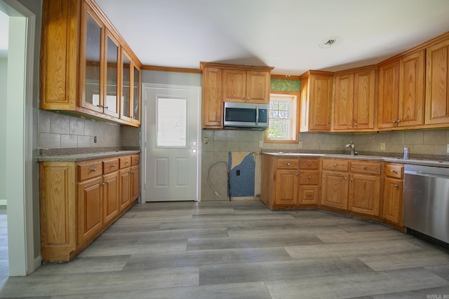 kitchen with decorative backsplash, light wood-type flooring, stainless steel appliances, crown molding, and sink