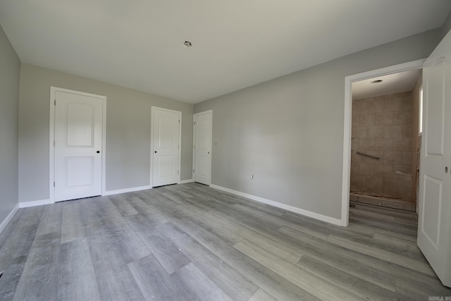 unfurnished bedroom featuring light wood-type flooring and ensuite bath