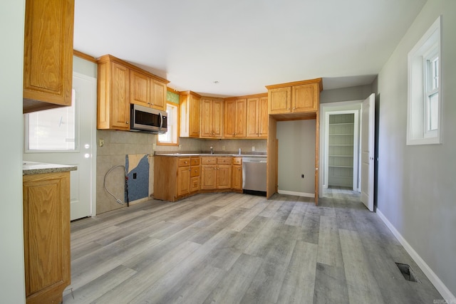 kitchen featuring decorative backsplash, sink, light hardwood / wood-style floors, and appliances with stainless steel finishes