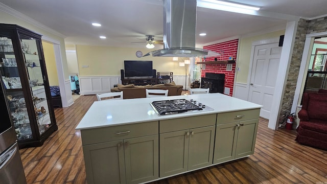 kitchen featuring a kitchen island, a fireplace, island exhaust hood, stainless steel gas cooktop, and crown molding