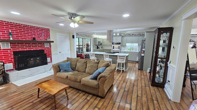 living room featuring crown molding, a fireplace, dark hardwood / wood-style flooring, and ceiling fan