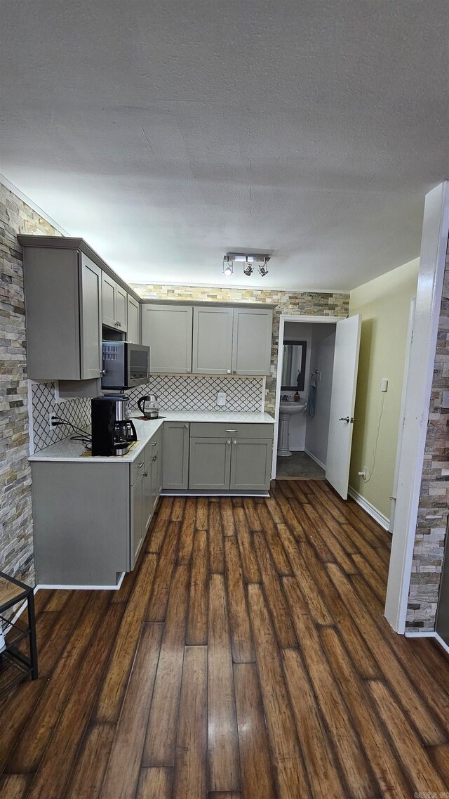 kitchen with gray cabinets, tasteful backsplash, and dark wood-type flooring