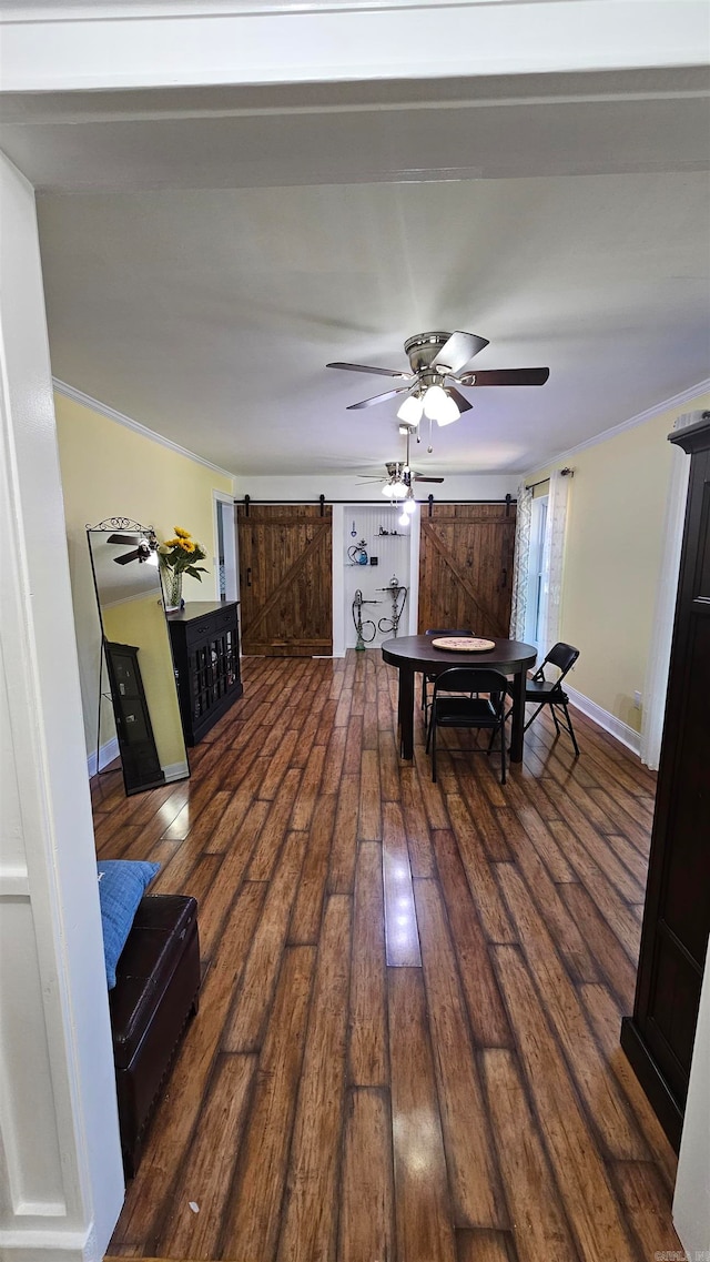 dining area featuring crown molding, dark wood-type flooring, a barn door, and ceiling fan