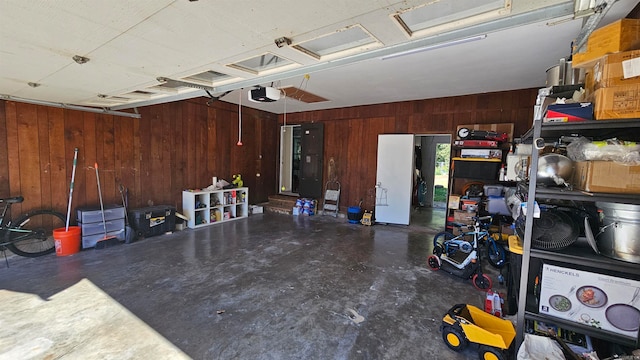 garage with a garage door opener and wood walls