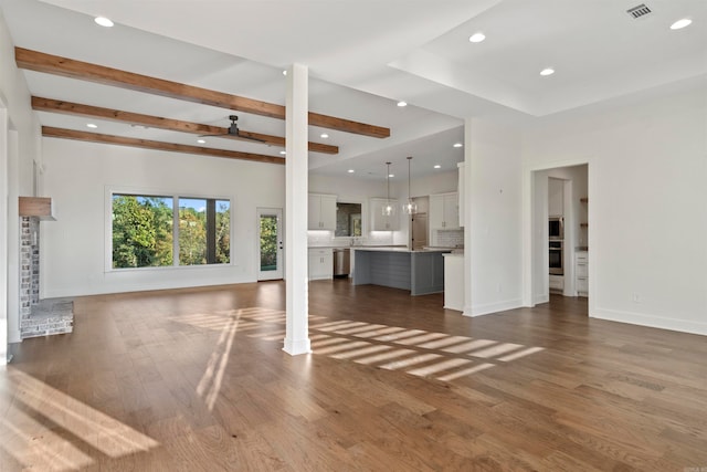 unfurnished living room with beamed ceiling, dark hardwood / wood-style flooring, ceiling fan, and a fireplace