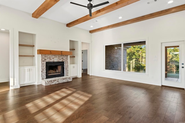 unfurnished living room featuring ceiling fan, beam ceiling, built in features, a fireplace, and dark hardwood / wood-style floors