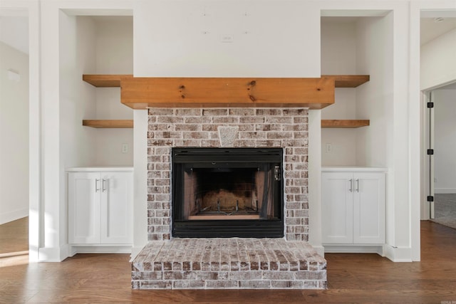 interior details with wood-type flooring and a brick fireplace