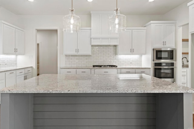 kitchen featuring a spacious island, white cabinets, stainless steel appliances, and decorative light fixtures