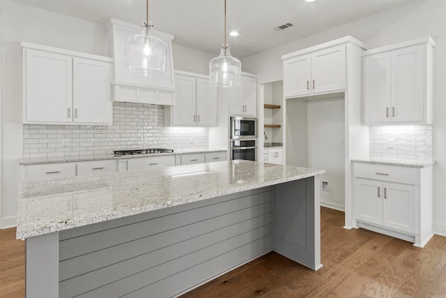 kitchen with white cabinetry, decorative light fixtures, decorative backsplash, appliances with stainless steel finishes, and light wood-type flooring