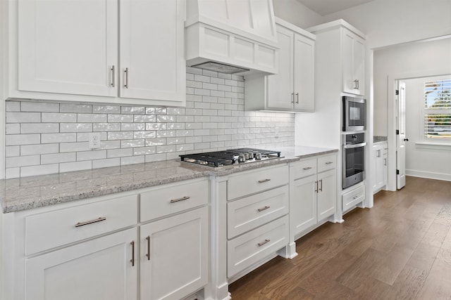 kitchen featuring premium range hood, white cabinets, dark hardwood / wood-style floors, tasteful backsplash, and stainless steel appliances