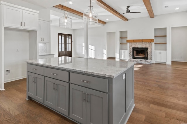 kitchen featuring a fireplace, dark wood-type flooring, decorative light fixtures, beamed ceiling, and gray cabinets