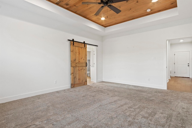 carpeted spare room with ceiling fan, a barn door, a raised ceiling, and wooden ceiling