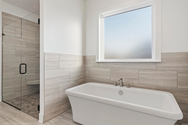 bathroom featuring tile walls and independent shower and bath