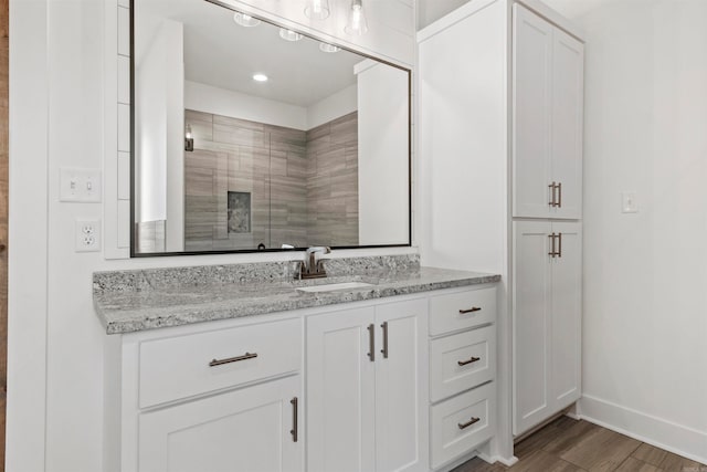 bathroom with hardwood / wood-style flooring, vanity, and a shower