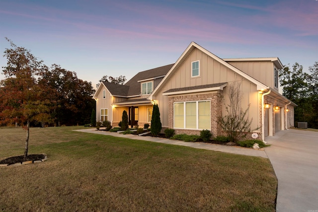 view of front of house featuring a yard, a garage, and central air condition unit