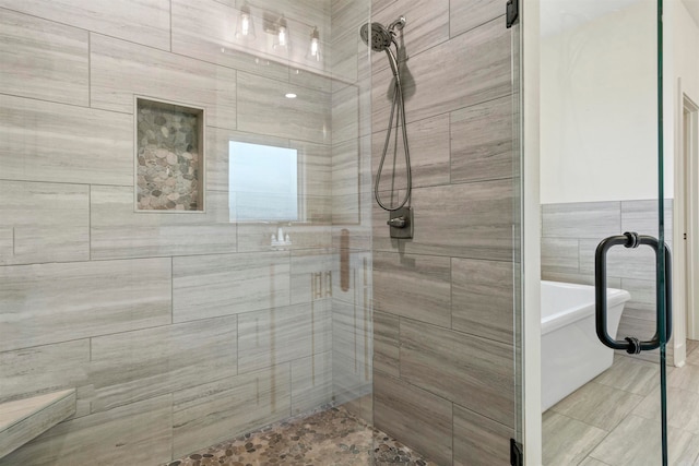 bathroom featuring separate shower and tub and tile walls