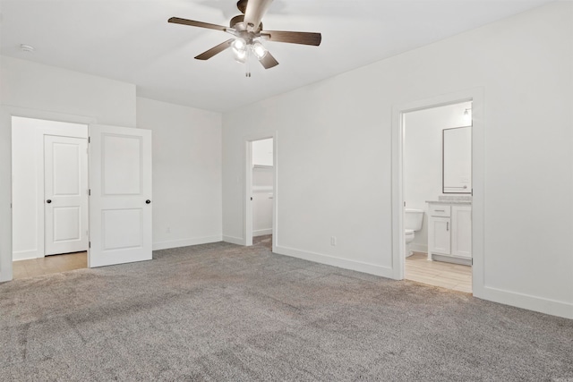 unfurnished bedroom with ceiling fan, a closet, light colored carpet, and ensuite bath