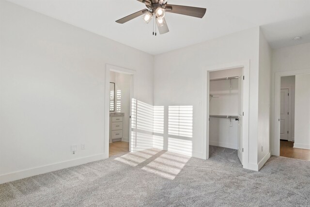 unfurnished bedroom featuring ceiling fan, a closet, light carpet, and a spacious closet