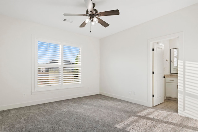 unfurnished bedroom featuring connected bathroom, light colored carpet, and ceiling fan