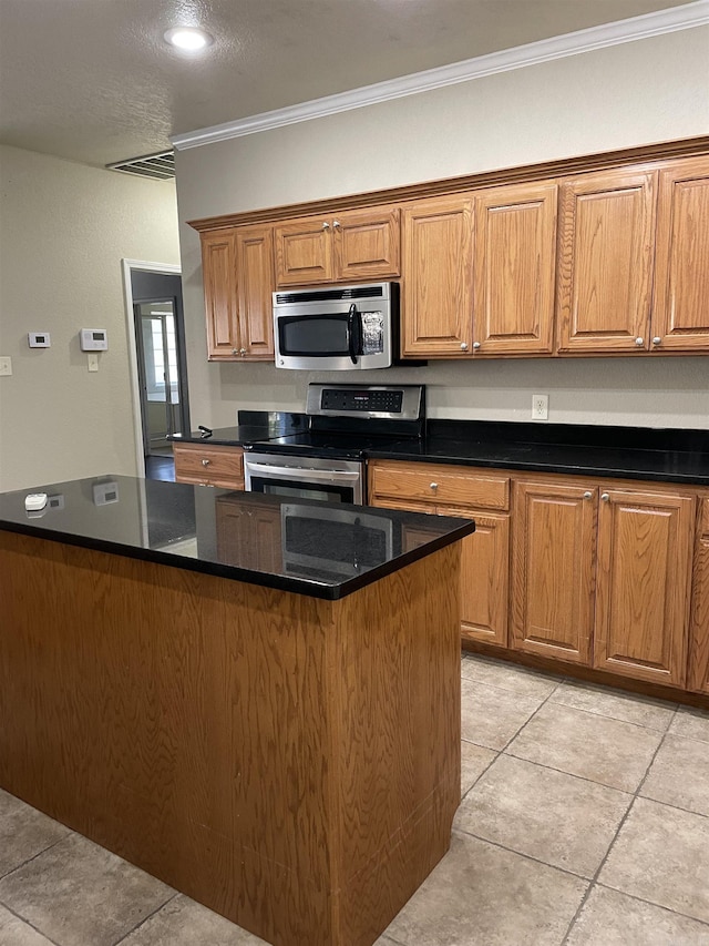 kitchen featuring dark stone countertops, stainless steel appliances, and ornamental molding