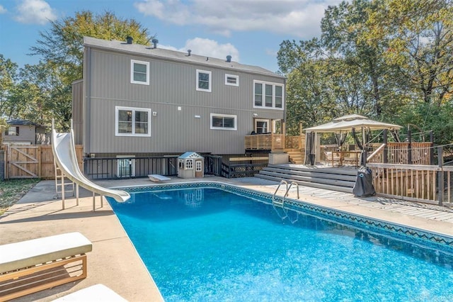 view of pool with a gazebo, a diving board, a wooden deck, and a water slide