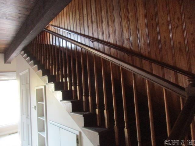 stairway featuring wooden walls, beamed ceiling, and wood ceiling