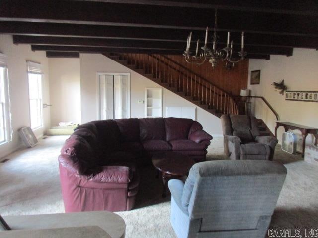 carpeted living room with beamed ceiling and a chandelier