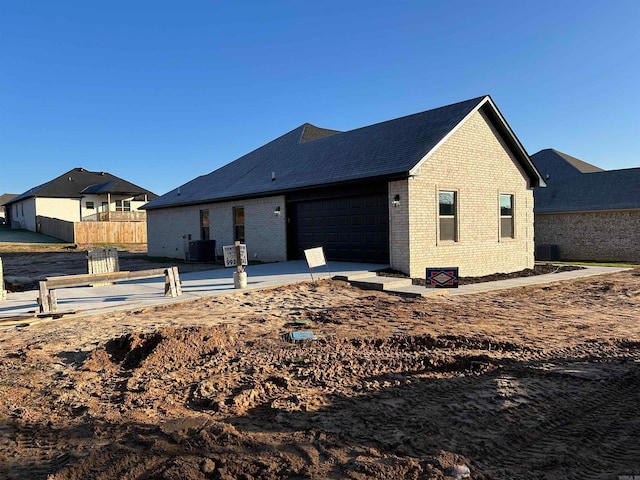 rear view of property featuring cooling unit and a garage