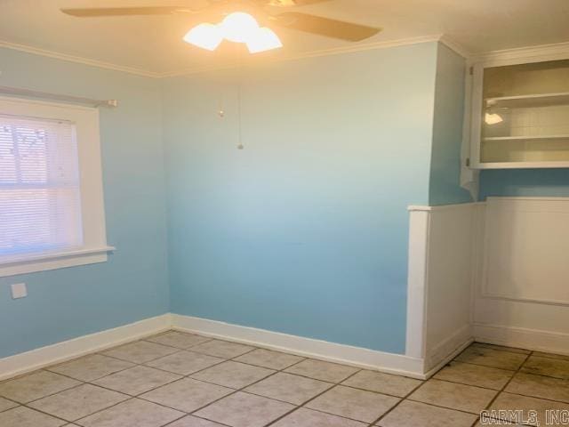 tiled empty room featuring ceiling fan and crown molding