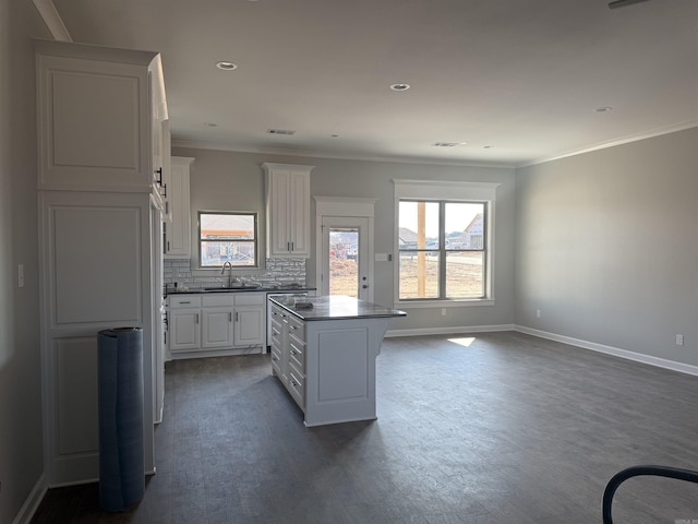 kitchen featuring tasteful backsplash, a center island, white cabinetry, and ornamental molding