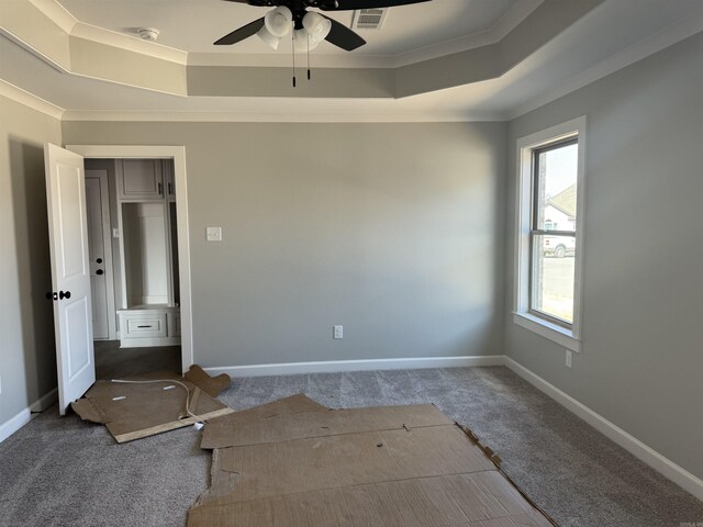 empty room with carpet, a tray ceiling, and baseboards