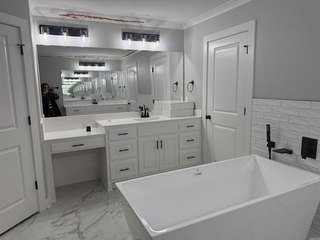 full bathroom featuring marble finish floor, ornamental molding, a freestanding tub, and vanity