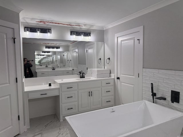 full bath featuring ornamental molding, marble finish floor, a freestanding tub, and vanity