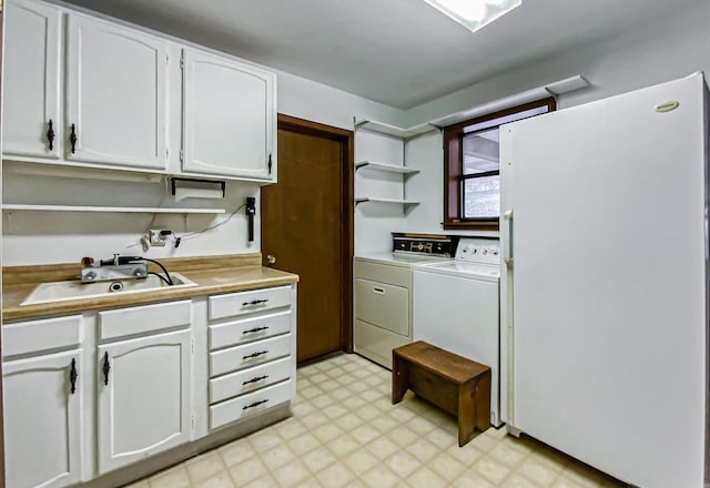 kitchen featuring washing machine and clothes dryer, sink, and white cabinets