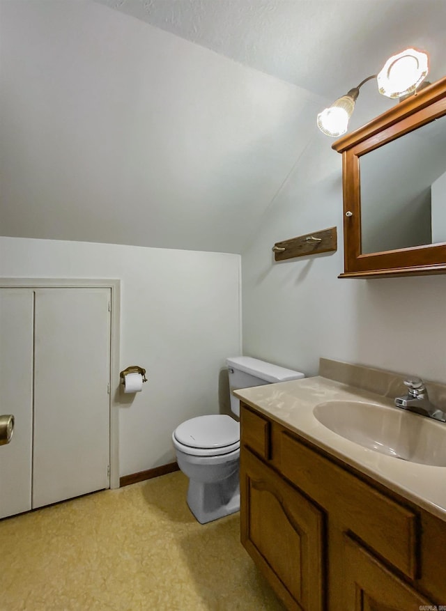 bathroom featuring toilet, vanity, and vaulted ceiling