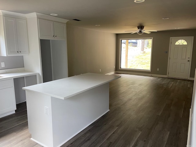 kitchen with light stone counters, ceiling fan, white cabinets, dark hardwood / wood-style floors, and a kitchen island