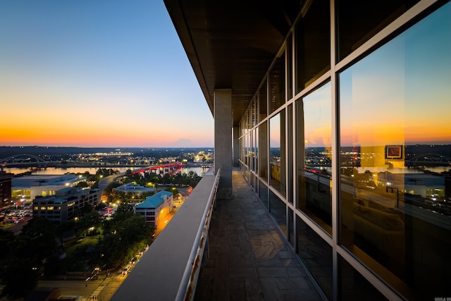 balcony at dusk featuring a water view