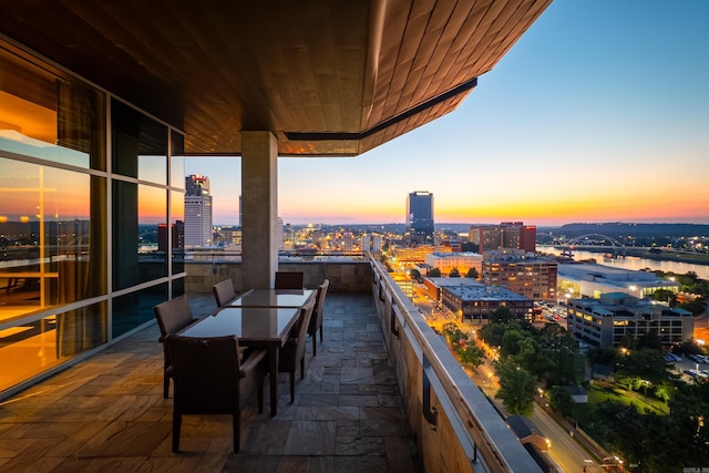 balcony at dusk featuring a water view