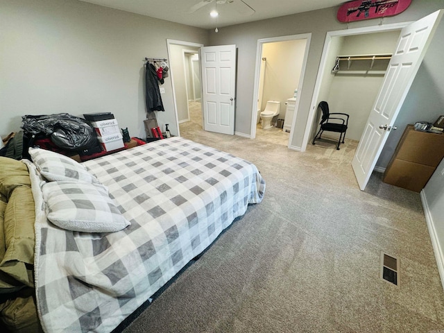 bedroom with a walk in closet, light colored carpet, a closet, and ceiling fan