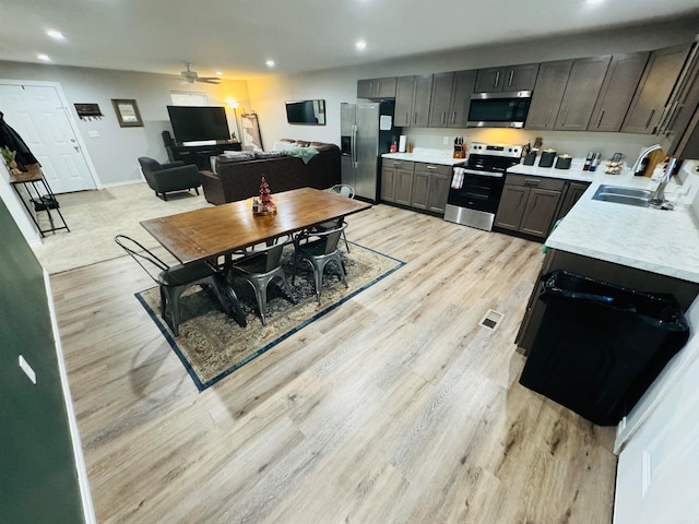 kitchen with ceiling fan, sink, stainless steel appliances, and light hardwood / wood-style floors