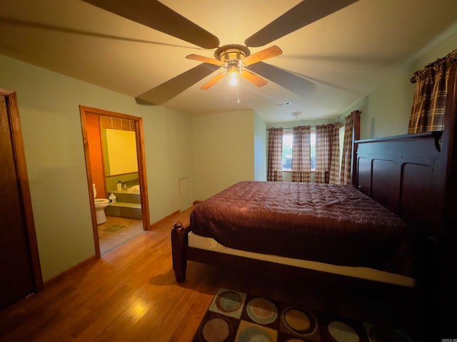 bedroom featuring light hardwood / wood-style floors, ceiling fan, and ensuite bathroom